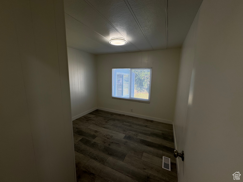 Empty room featuring dark wood-style flooring and a textured ceiling