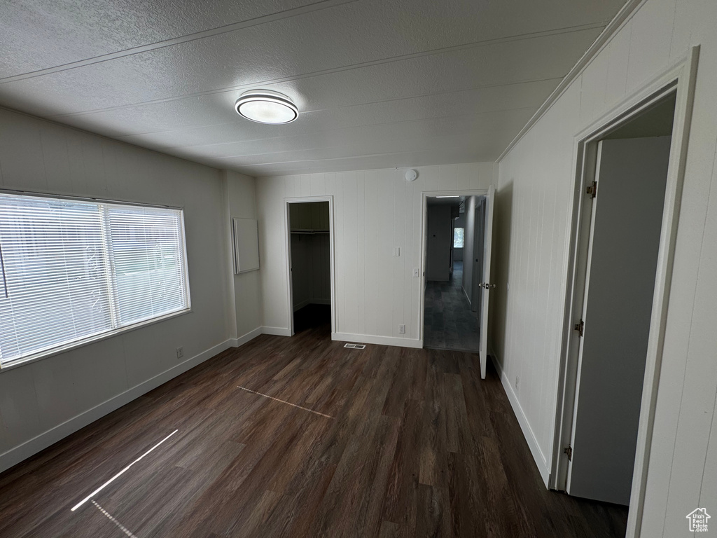 Unfurnished bedroom featuring dark wood-type flooring, a closet, and a textured ceiling