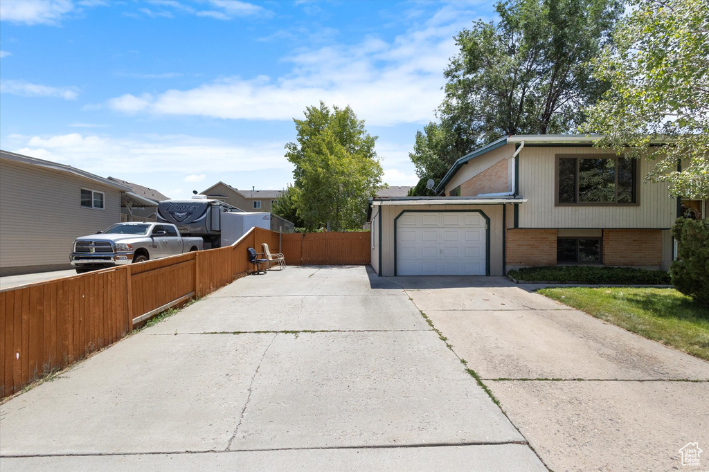View of side of property with driveway, brick siding, and a garage