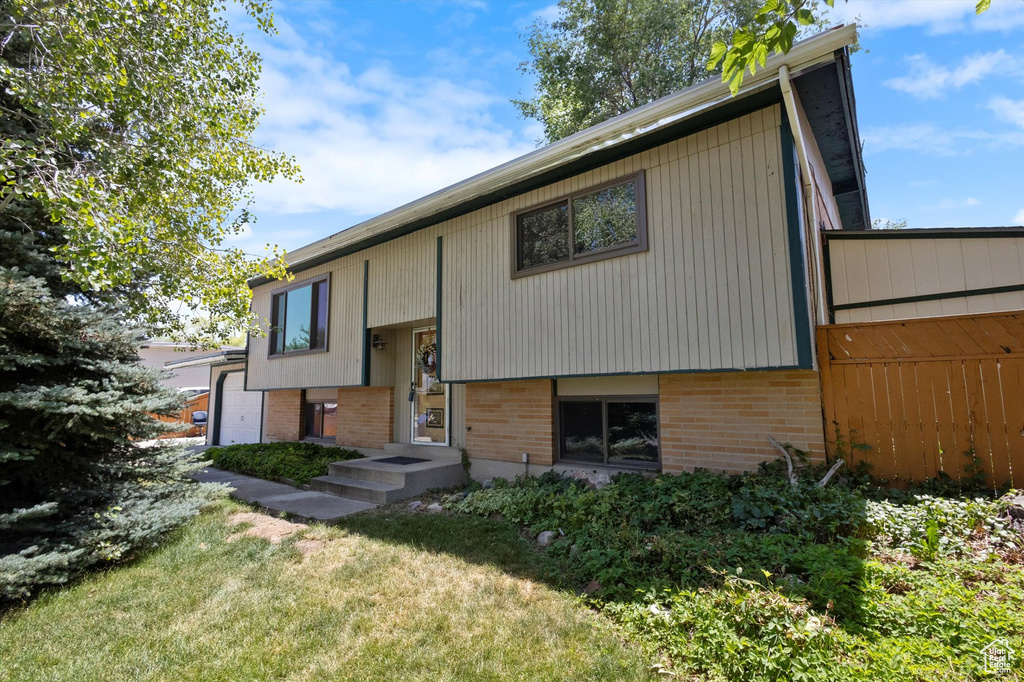Bi-level home featuring a front yard and brick siding
