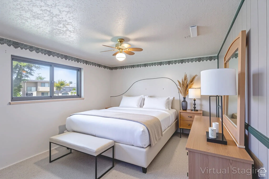 Bedroom with a textured ceiling, light colored carpet, and a ceiling fan