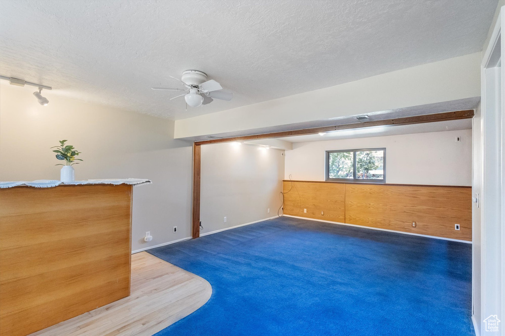 Carpeted spare room featuring a ceiling fan, a textured ceiling, and track lighting