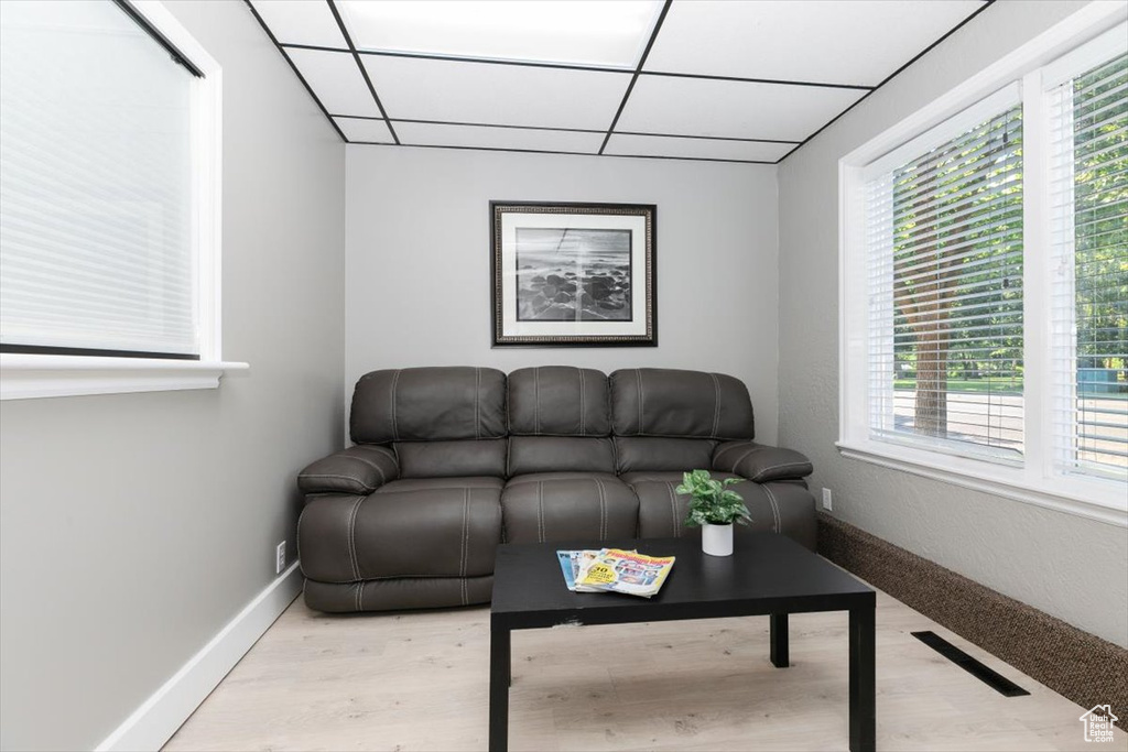 Living area with a drop ceiling and light wood-style flooring