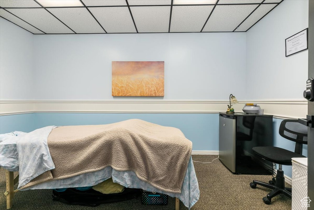 Bedroom with freestanding refrigerator, carpet flooring, and a paneled ceiling