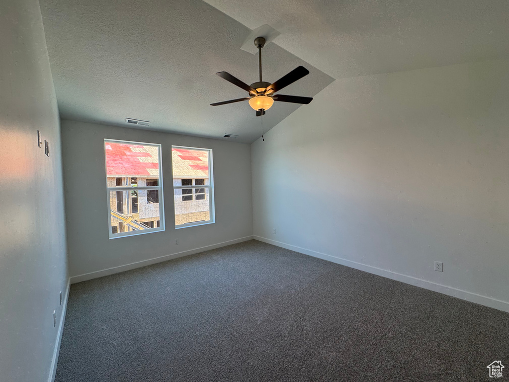 Unfurnished room with vaulted ceiling, a textured ceiling, carpet floors, and a ceiling fan