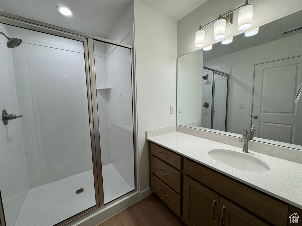 Bathroom featuring a shower stall, wood finished floors, and vanity