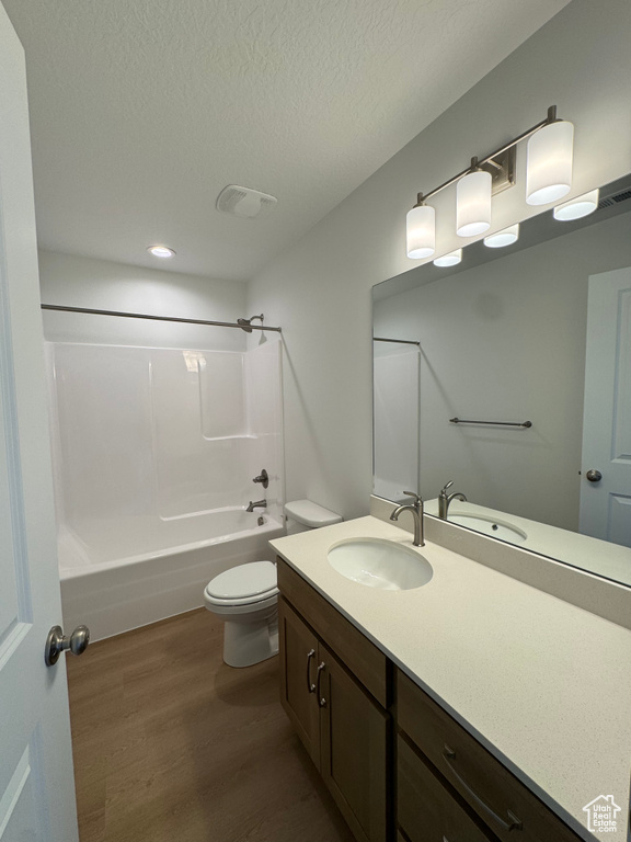 Bathroom with wood finished floors, vanity, bathing tub / shower combination, a textured ceiling, and recessed lighting