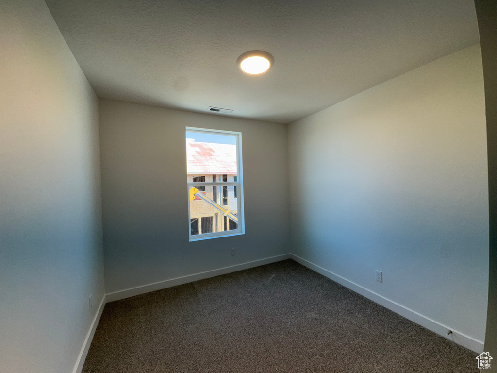 Empty room featuring dark carpet