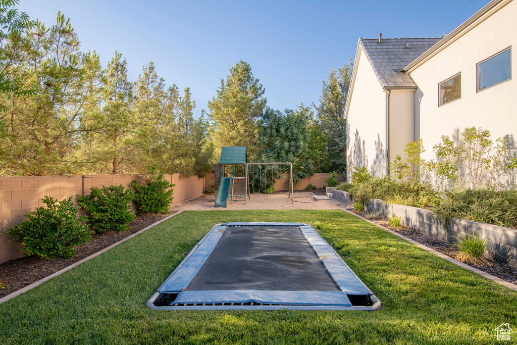 Fenced backyard with a trampoline and a playground