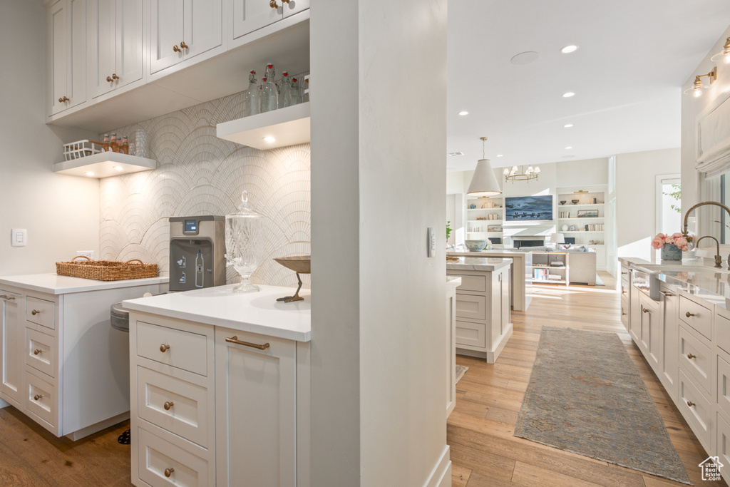 Kitchen with light wood-style floors, decorative backsplash, light countertops, and recessed lighting