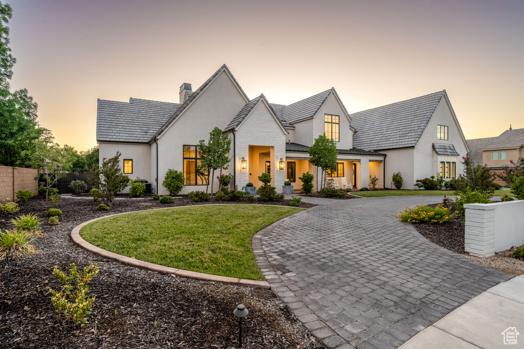 View of front of home with curved driveway, stucco siding, a chimney, a standing seam roof, and a metal roof