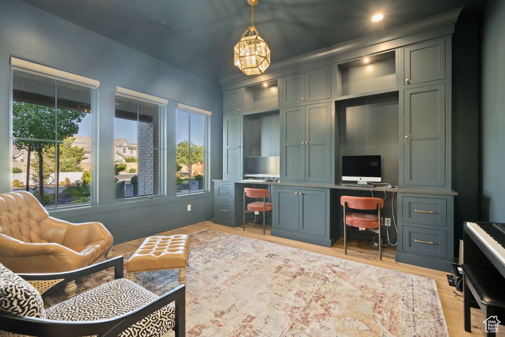 Office featuring light wood-type flooring, built in study area, and a chandelier