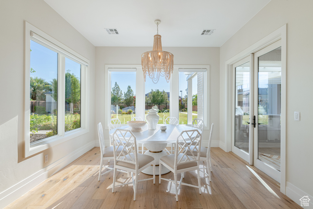 Sunroom / solarium featuring a chandelier, plenty of natural light, and french doors