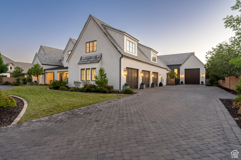 Modern farmhouse featuring decorative driveway, stucco siding, and an outbuilding