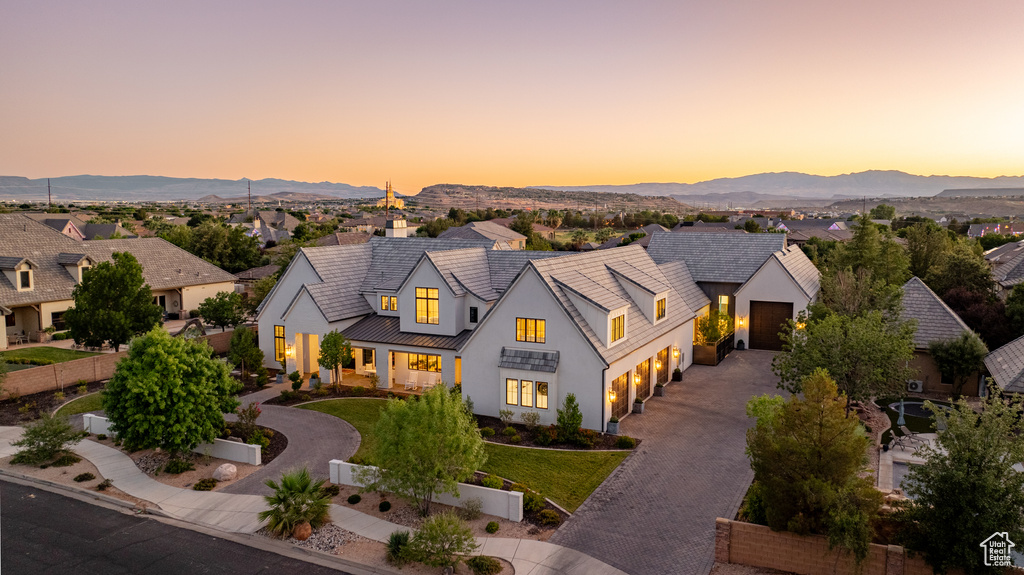 Modern farmhouse featuring driveway, a garage, stucco siding, a standing seam roof, and a mountain view