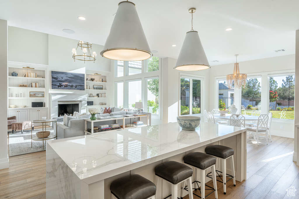 Kitchen featuring a chandelier, plenty of natural light, light stone counters, light wood finished floors, and recessed lighting