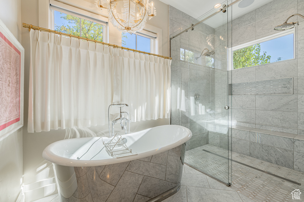 Bathroom with a chandelier, plenty of natural light, and a freestanding bath