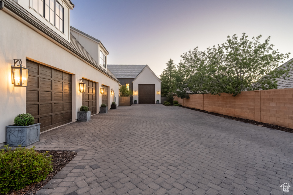 Garage at dusk featuring decorative driveway