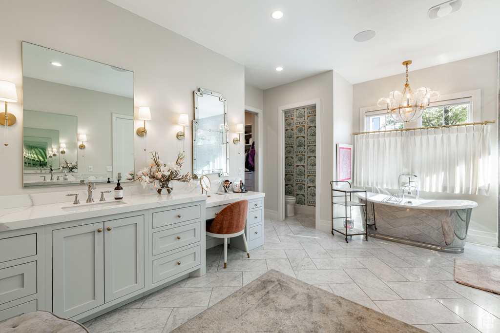 Full bath with vanity, a chandelier, a freestanding tub, recessed lighting, and marble finish floors
