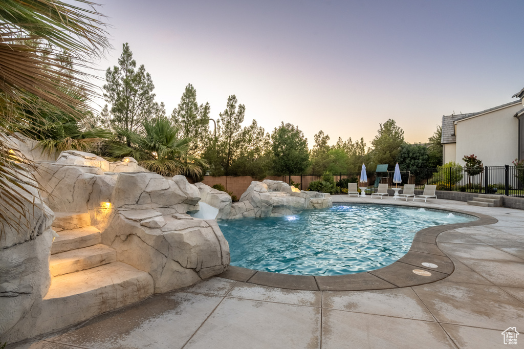 Pool at dusk featuring a patio