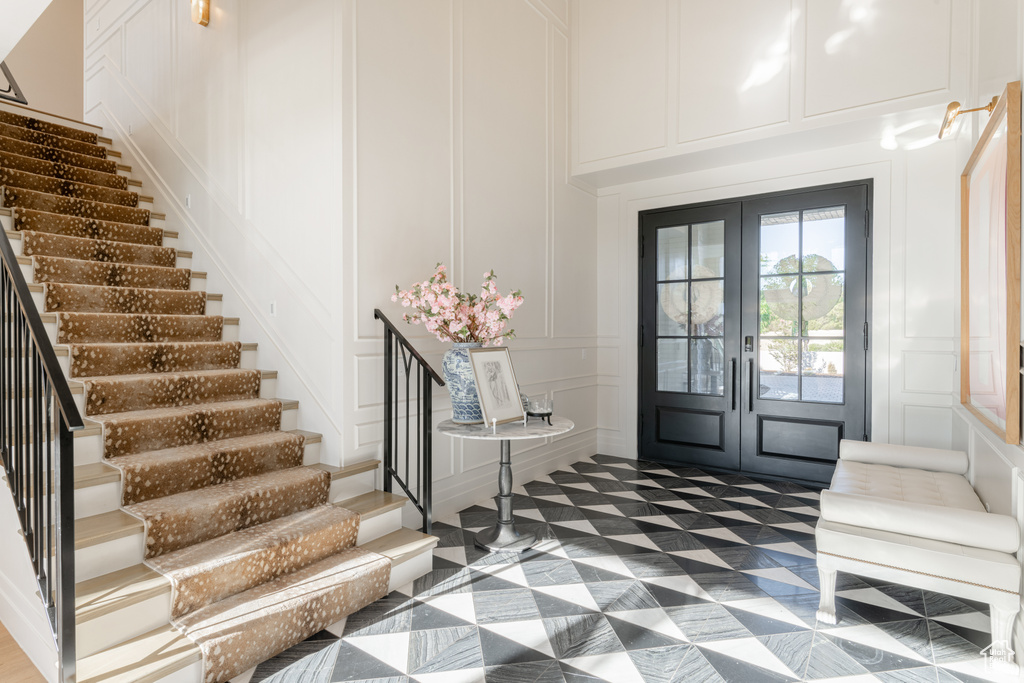 Entryway with a decorative wall, stairway, and french doors