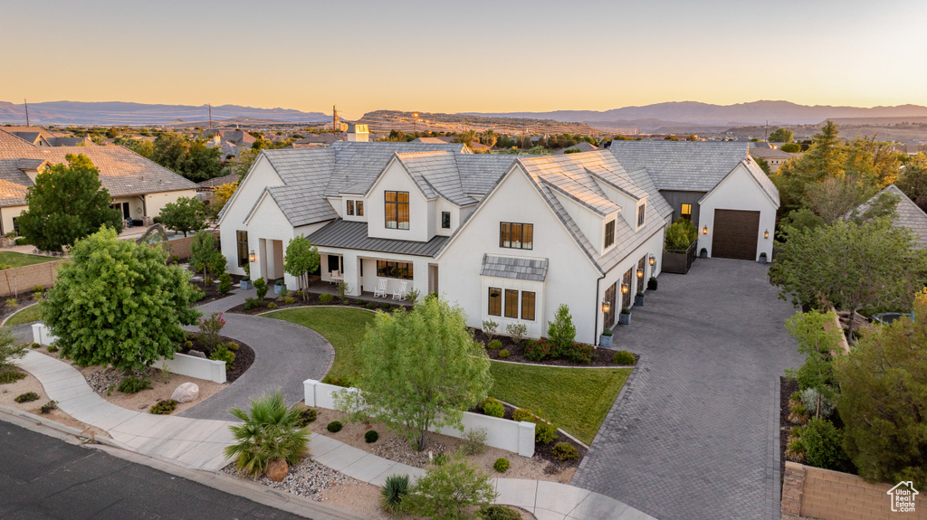 Modern farmhouse style home featuring driveway, stucco siding, a garage, a standing seam roof, and a mountain view