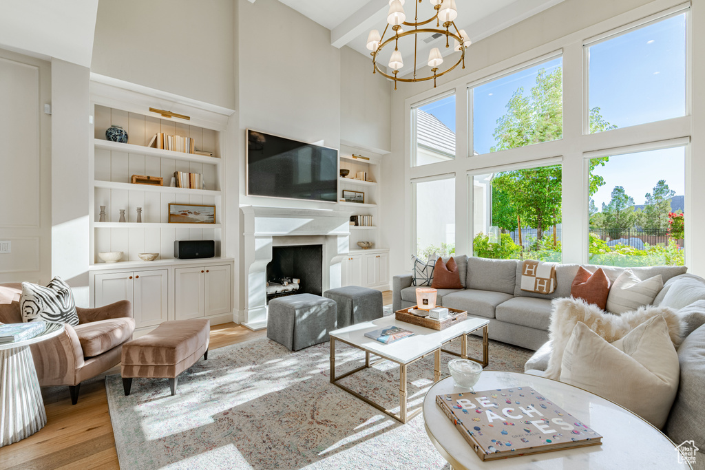 Living room featuring a high ceiling, a chandelier, wood finished floors, built in shelves, and a premium fireplace