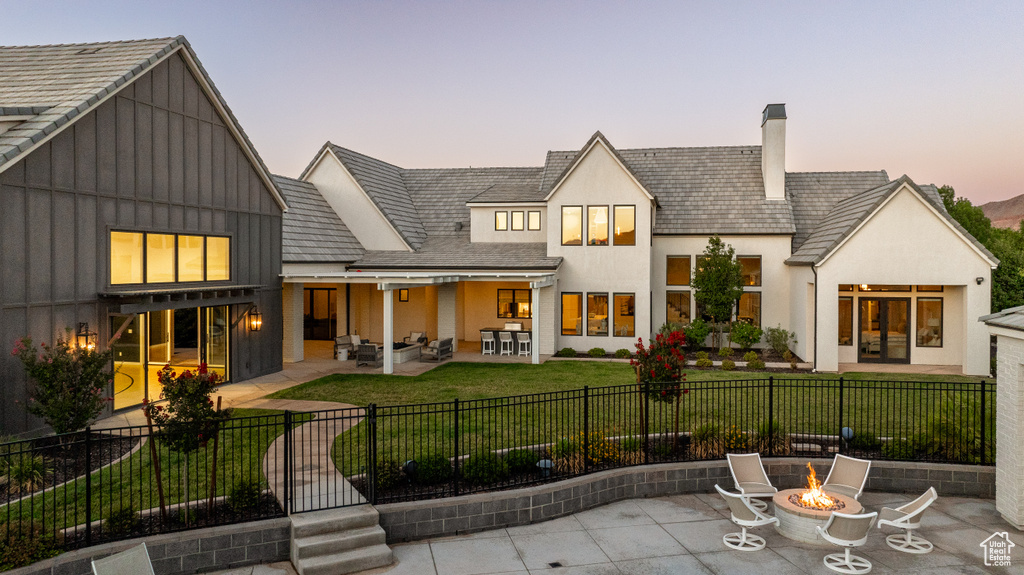 Rear view of property featuring a patio area, a fenced front yard, a chimney, and an outdoor living space with a fire pit
