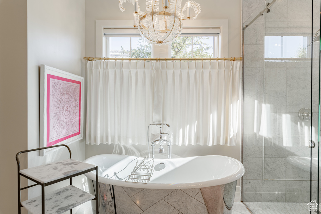 Bathroom featuring a soaking tub, a chandelier, and a stall shower