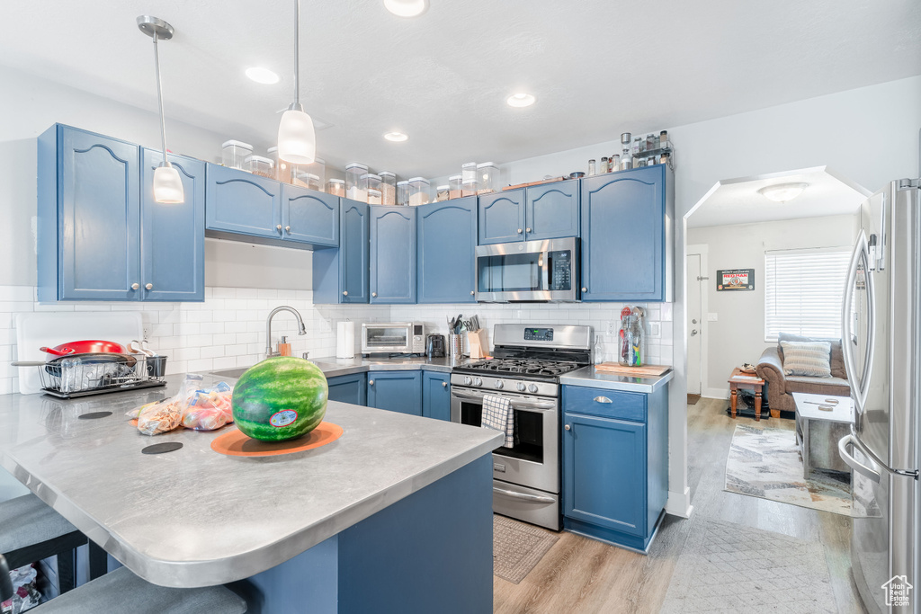Kitchen with stainless steel appliances, blue cabinetry, a peninsula, a kitchen breakfast bar, and arched walkways