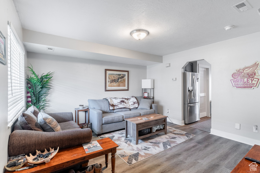 Living area with wood finished floors, arched walkways, and a textured ceiling