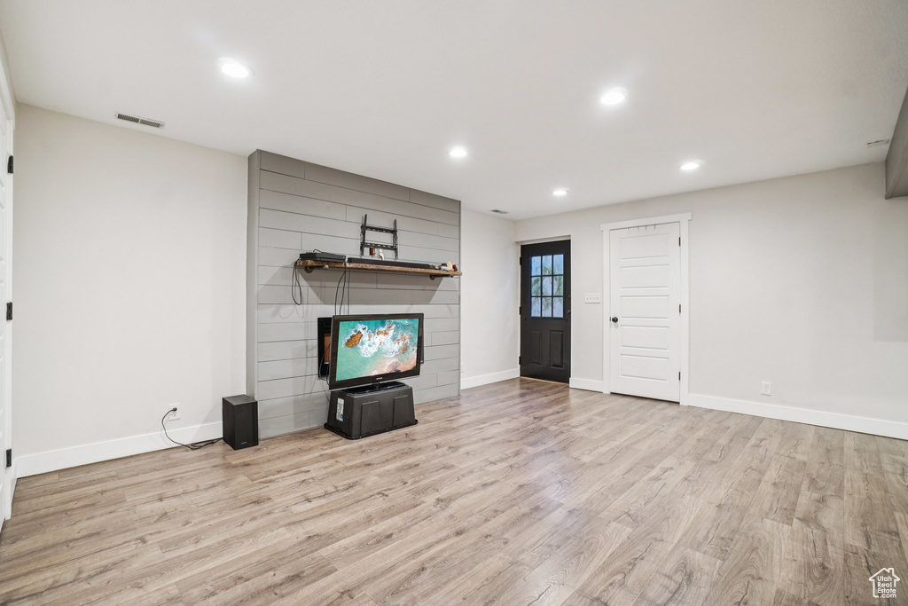 Unfurnished living room with a large fireplace, wood finished floors, and recessed lighting