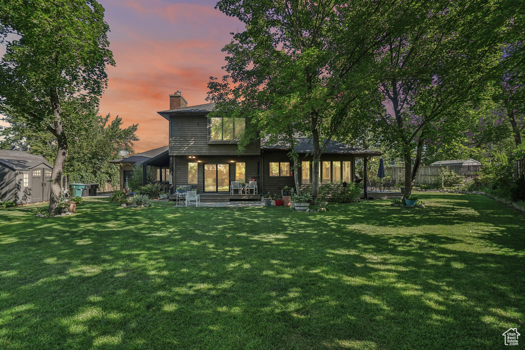 Back of house with a storage shed, a fenced backyard, a chimney, and a patio area