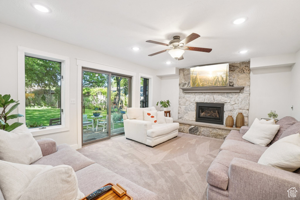 Carpeted living area featuring recessed lighting, a stone fireplace, and a ceiling fan