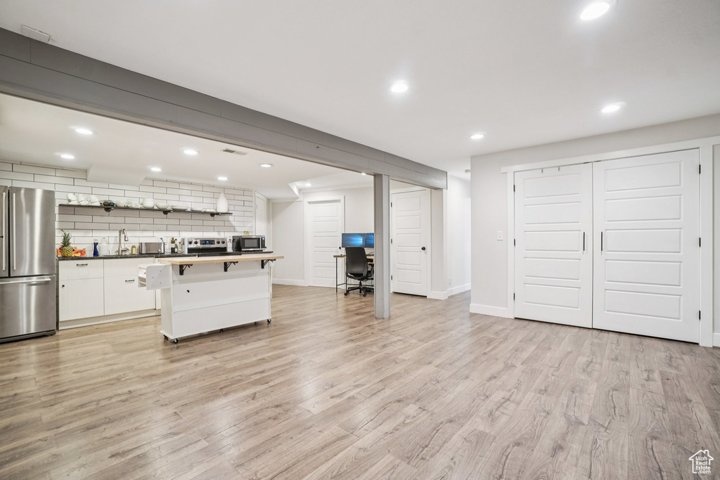 Kitchen featuring appliances with stainless steel finishes, decorative backsplash, white cabinets, light wood finished floors, and recessed lighting