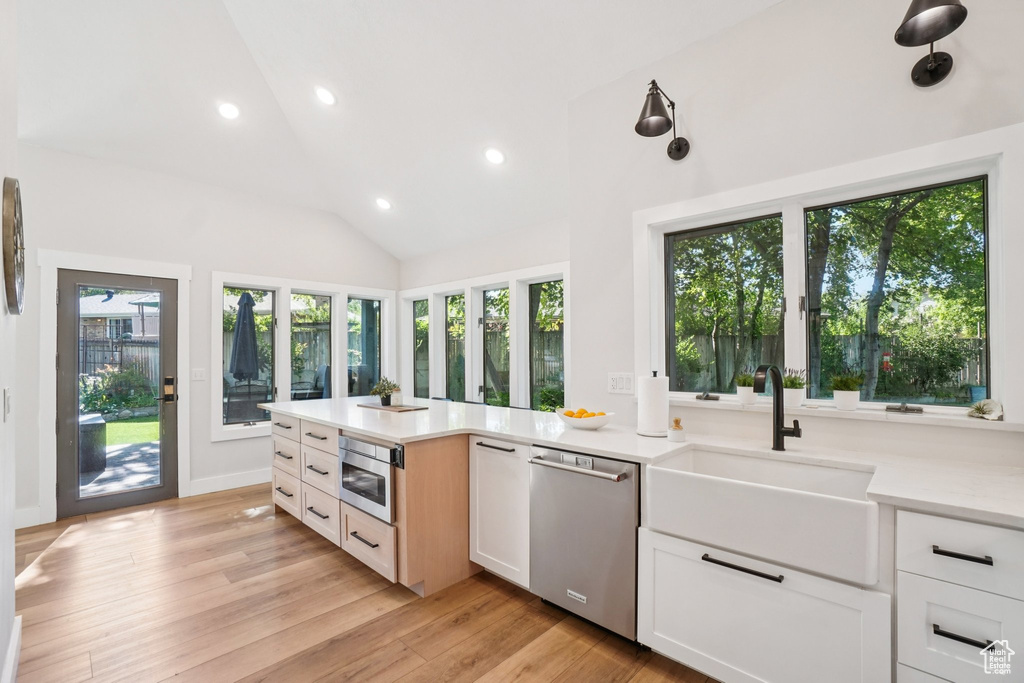 Kitchen with recessed lighting, stainless steel dishwasher, light countertops, light wood-style floors, and white cabinetry