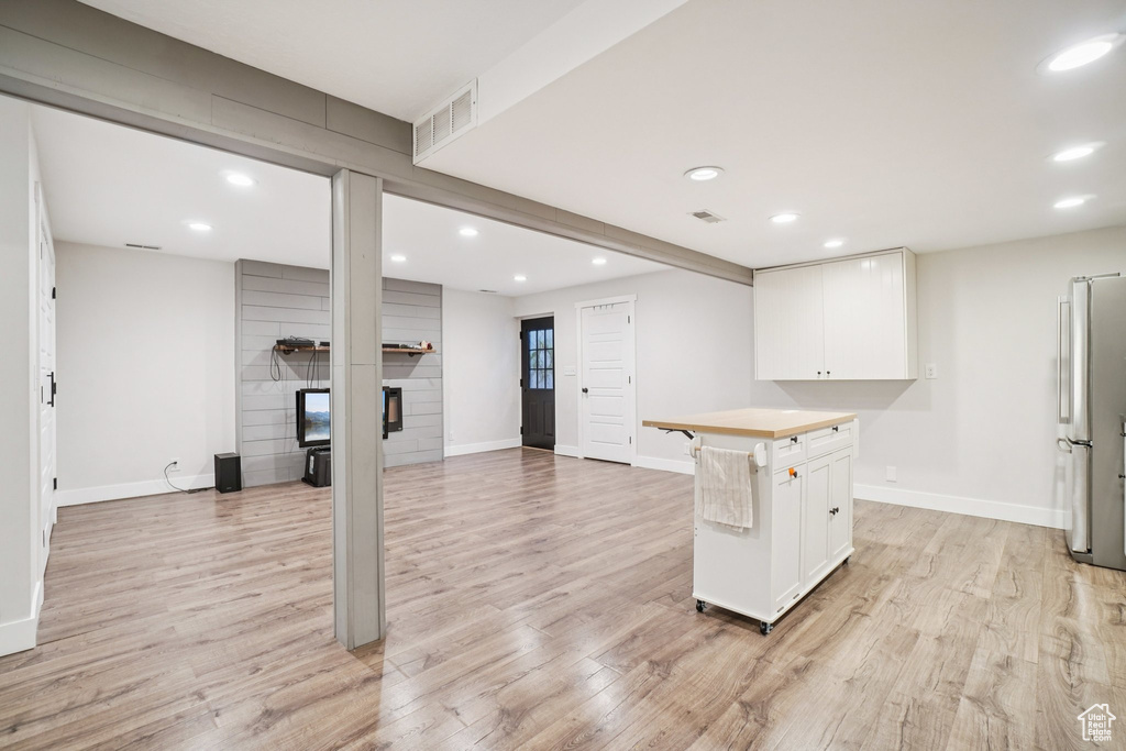 Kitchen with white cabinetry, recessed lighting, light wood finished floors, and a large fireplace