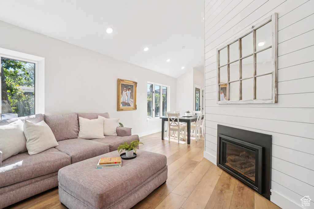 Living area with recessed lighting, light wood-type flooring, a glass covered fireplace, and vaulted ceiling