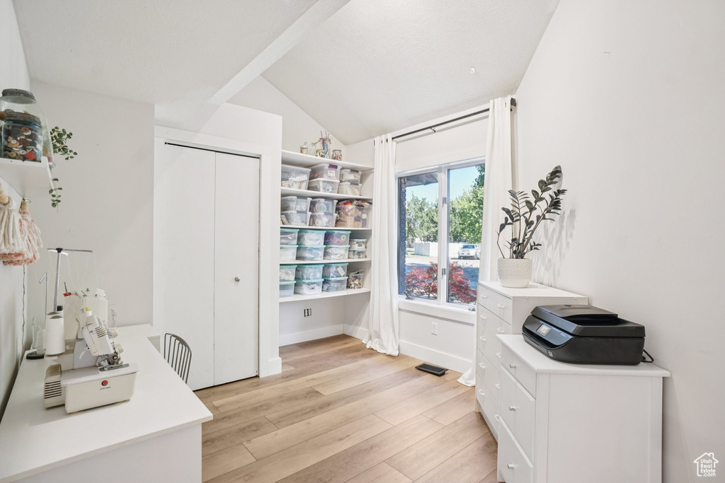 Office with light wood-type flooring and vaulted ceiling