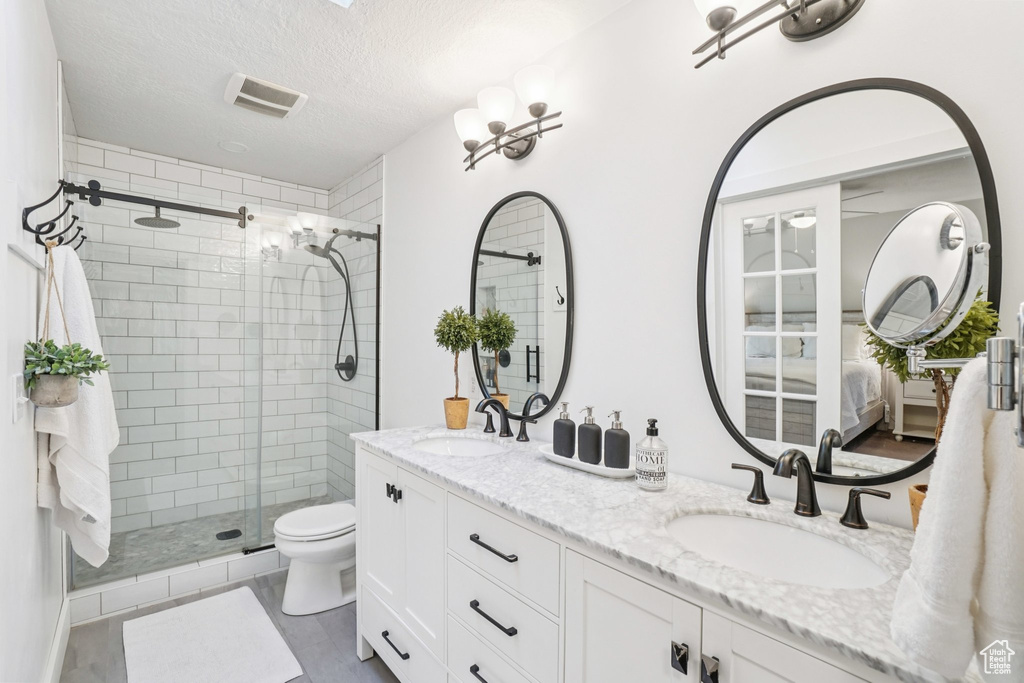 Bathroom with a shower stall, double vanity, and a textured ceiling