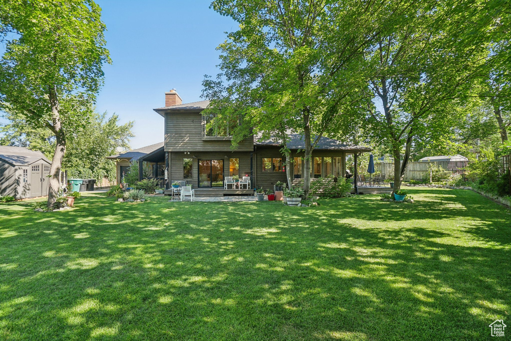 Rear view of house featuring a storage unit, a patio, a chimney, and a fenced backyard