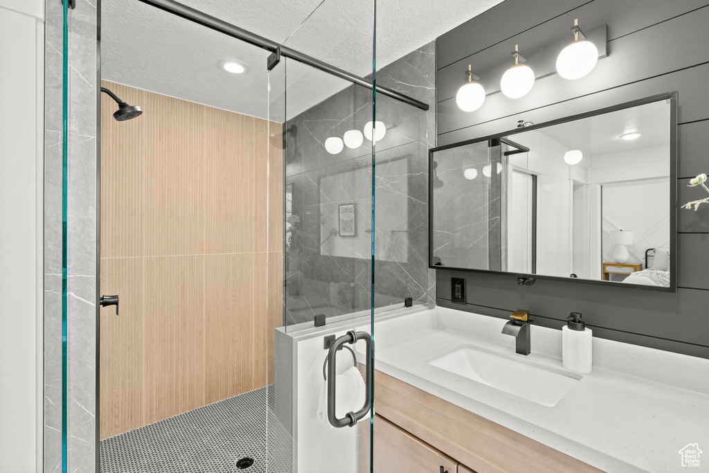 Ensuite bathroom with a shower stall, vanity, and a textured ceiling