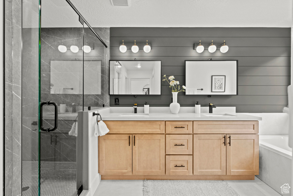 Bathroom with double vanity, a stall shower, and a tub to relax in