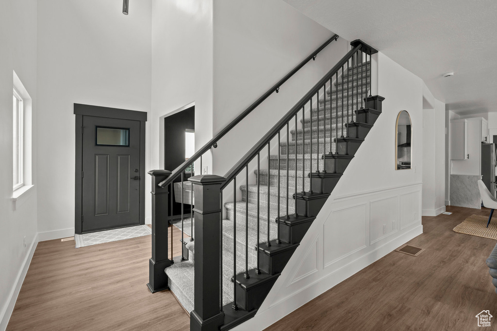 Entryway featuring stairs, wood finished floors, a high ceiling, and plenty of natural light