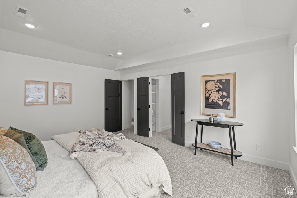 Bedroom with light carpet, recessed lighting, and a walk in closet