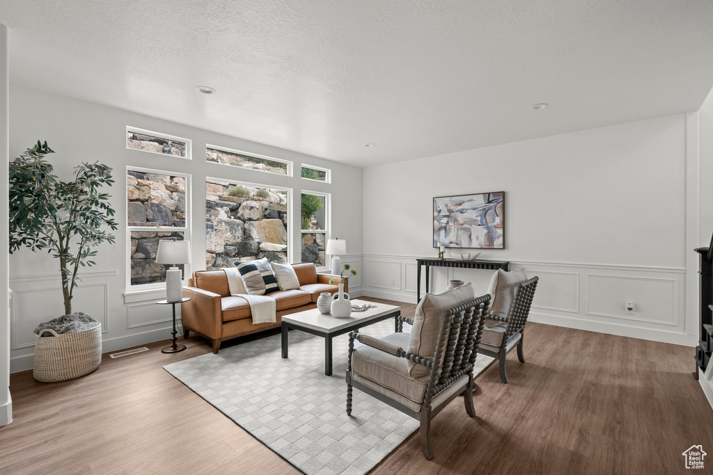 Living room featuring wood finished floors, a decorative wall, and wainscoting