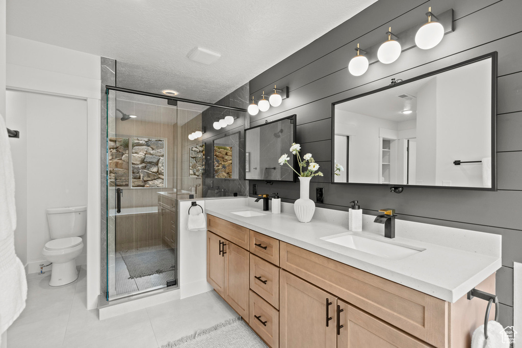Bathroom featuring double vanity, a stall shower, tile patterned flooring, and a textured ceiling
