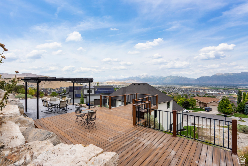 Wooden deck with a mountain view, a pergola, and outdoor dining area