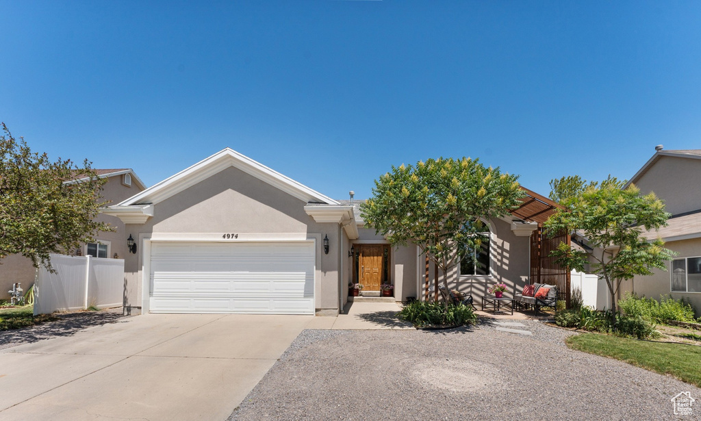 View of front of property with concrete driveway, an attached garage, and stucco siding