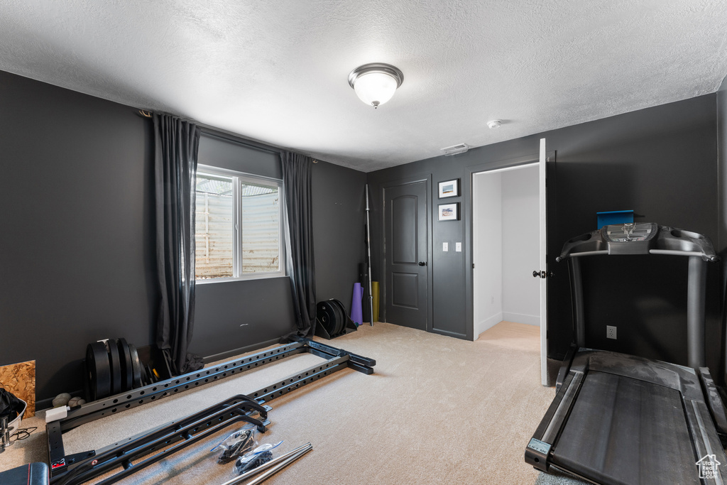 Workout area with carpet flooring and a textured ceiling